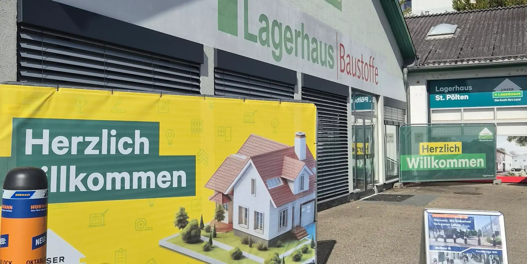 Lagerhaus St. Pölten mit Willkommensbanner und Hausabbildung vor dem Eingang