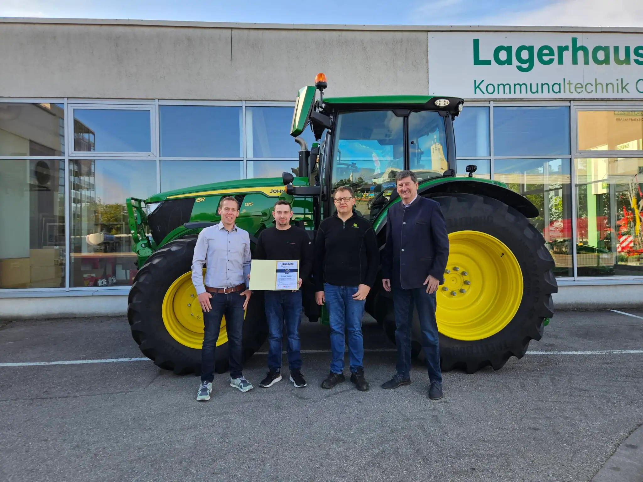 Niklas mit seinen Kollegen vor einem John Deere Traktor