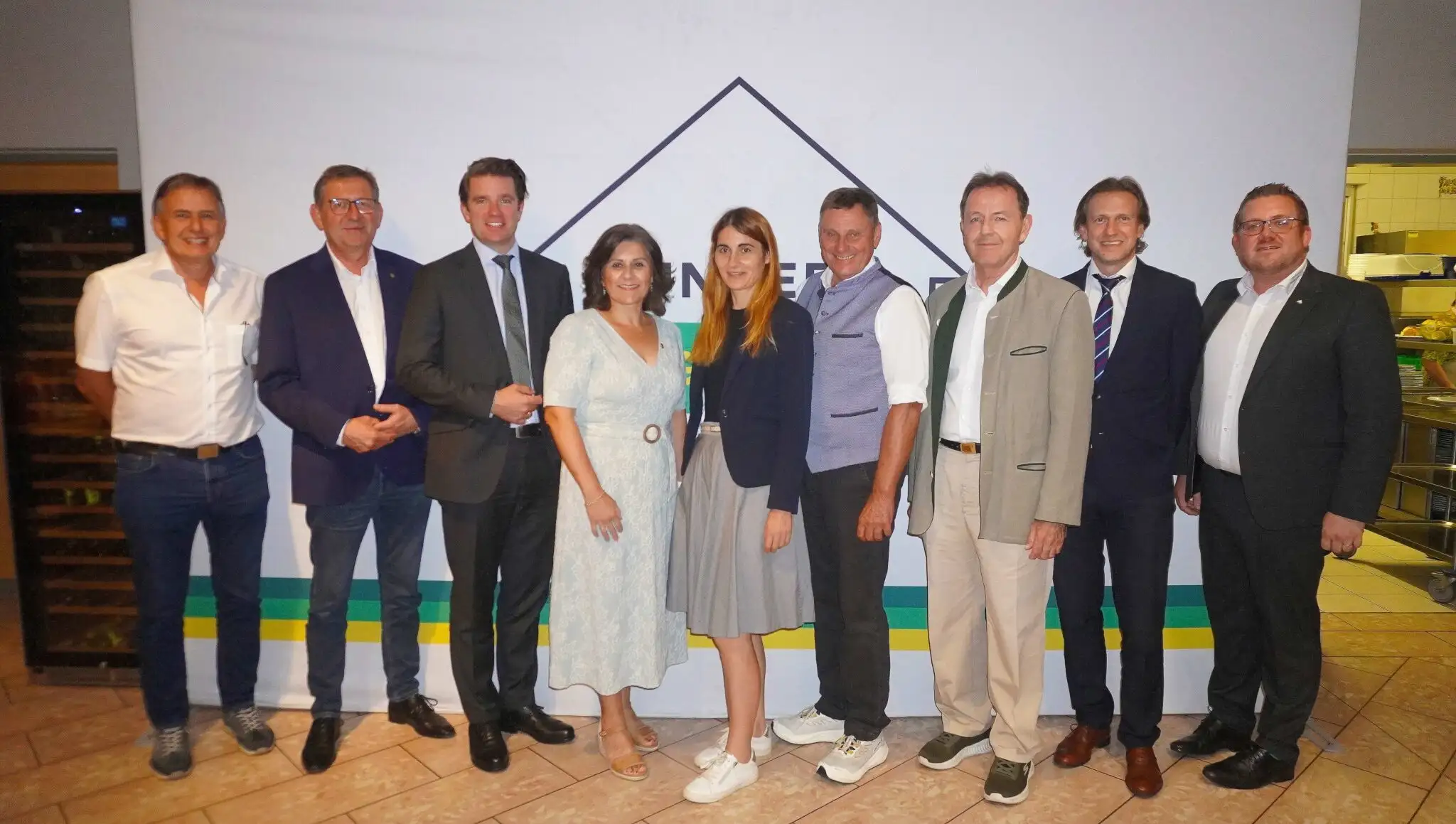 Gruppe von Personen vor einer Wand mit Logo, v.l.n.r. unbekannt, unbekannt, unbekannt, unbekannt, unbekannt, unbekannt, unbekannt, unbekannt