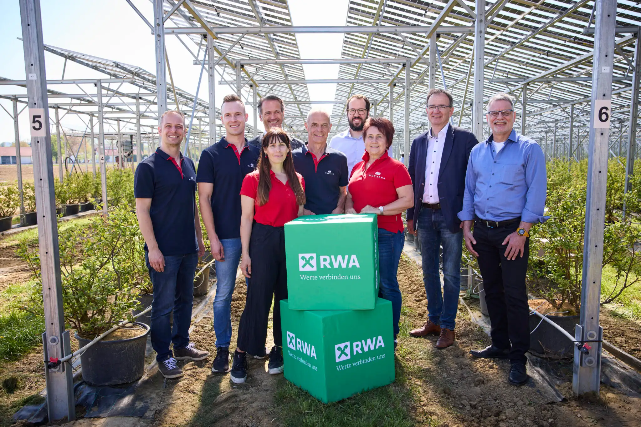 RWA-Mitarbeiter mit grünen Kisten vor Gewächshaus in Österreich