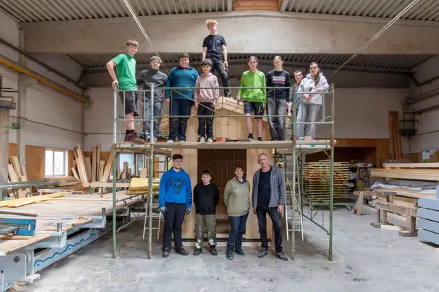 Die Schülergruppe steht auf einem Gerüst in einer Werktstatt.