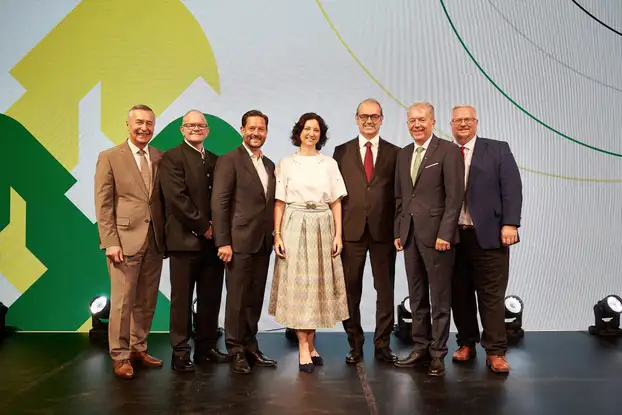 eine Gruppe von Menschen steht auf einer Bühne ud posiert für ein Foto.