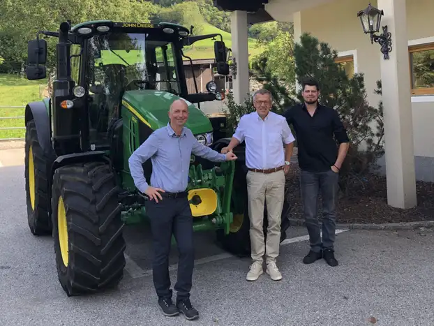 drei Herren vor einem John Deere Traktor